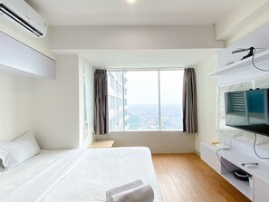 Habitación de hotel con una cama grande, un televisor y vistas a la ciudad desde la ventana.
