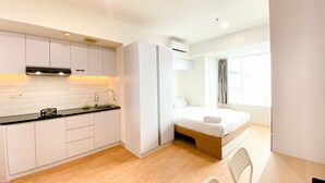 Ein kleines Hotelzimmer mit einer Küchenzeile, einem Bett und einem Fenster.