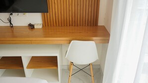 Een houten bureau met een televisie, een witte stoel en een wand van houten latten.