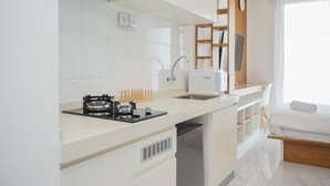 Een moderne keuken met een inbouwfornuis, spoelbak en vaatwasser. Daarboven staat een houten schapunit en een raam met gordijnen.