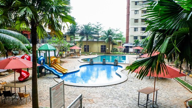 Un área de piscina con tobogán, asientos y un cartel.