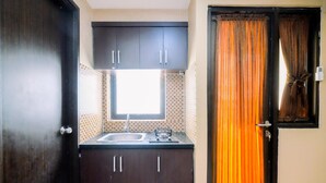 Una cocina compacta con armarios oscuros, una ventana y un lavamanos.
