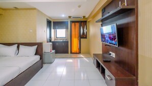 Una habitación de hotel con cama, televisión, kitchenette y baño.