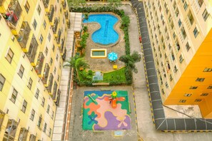 Un quartier résidentiel doté d’une piscine, d’une aire de jeux pour enfants et d’un immeuble jaune à plusieurs étages.