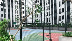Een basketbalveld omringd door een hek van gaas, met een gebouw op de achtergrond.