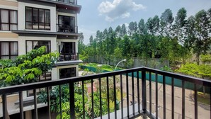 A multi-story building with balconies, a green garden area, and a clear sky. - Comfort 2Br At Asatti Apartment (Pagedangan)