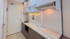 Une petite cuisine avec une porte blanche, un évier et un panneau indiquant qu’il est interdit de fumer.
