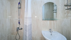 Une salle de bain avec une douche, un lavabo et une étagère en verre.