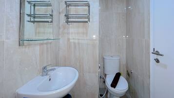 A bathroom with a white sink, a mirror, a toilet, and a glass shower enclosure.