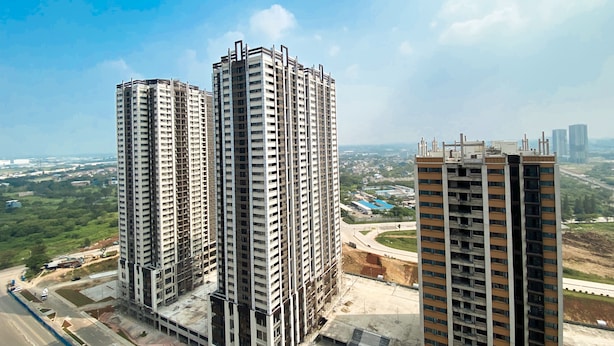 Complejo de edificios altos con varios pisos, rodeado de paisaje verde y cielo despejado.