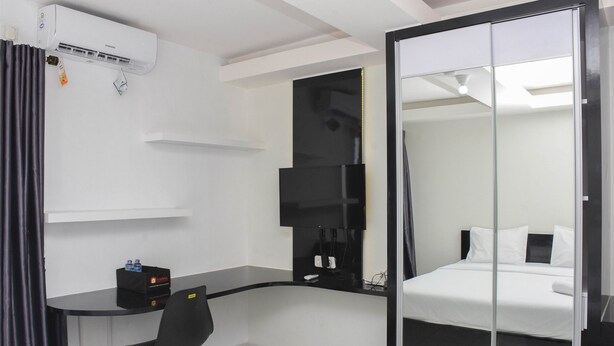 Una habitación de hotel con cama, escritorio, silla, televisor y armario.