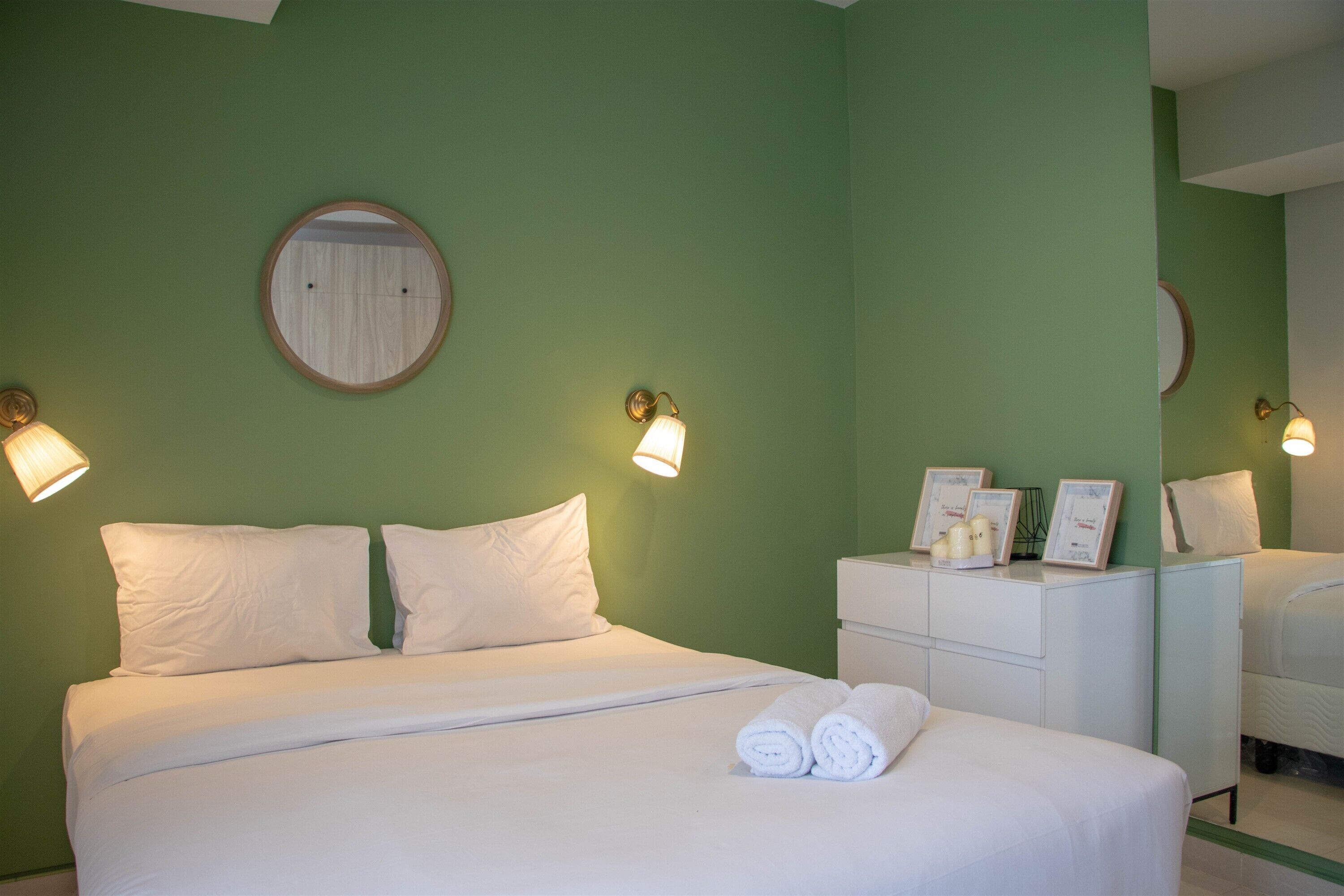 A hotel room with a bed, two bedside tables, and a mirror.