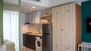 A compact kitchen with a washing machine, a refrigerator, and wooden cabinets. - Well Appointed And Homey Studio At West Vista Apartment (Jakarta)