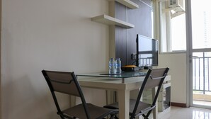 Uma cozinha moderna com uma mesa de vidro, duas cadeiras, uma TV e garrafas de água.