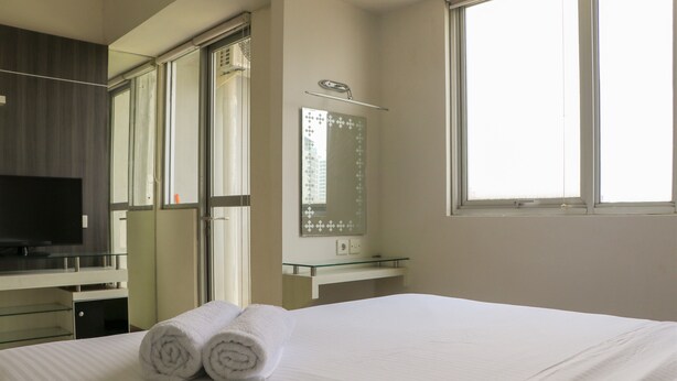 Quarto de hotel com uma cama, televisão, espelho e janela.