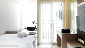 Une chambre d’hôtel équipée d’un lit, d’un bureau, d’une chaise, d’une télévision et d’une fenêtre avec des stores.