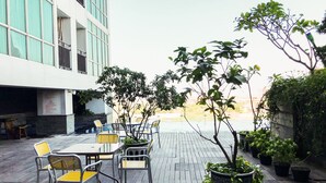 Une terrasse avec des sièges, des plantes en pot et une vue sur un bâtiment en arrière-plan.