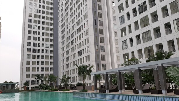 Un edificio moderno de gran altura con una piscina al frente.