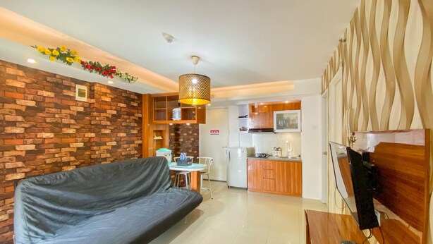 A modern living room with a sofa, a dining area, and a kitchen. - Comfort And Homey 3Br Bassura City Apartment (Jakarta)