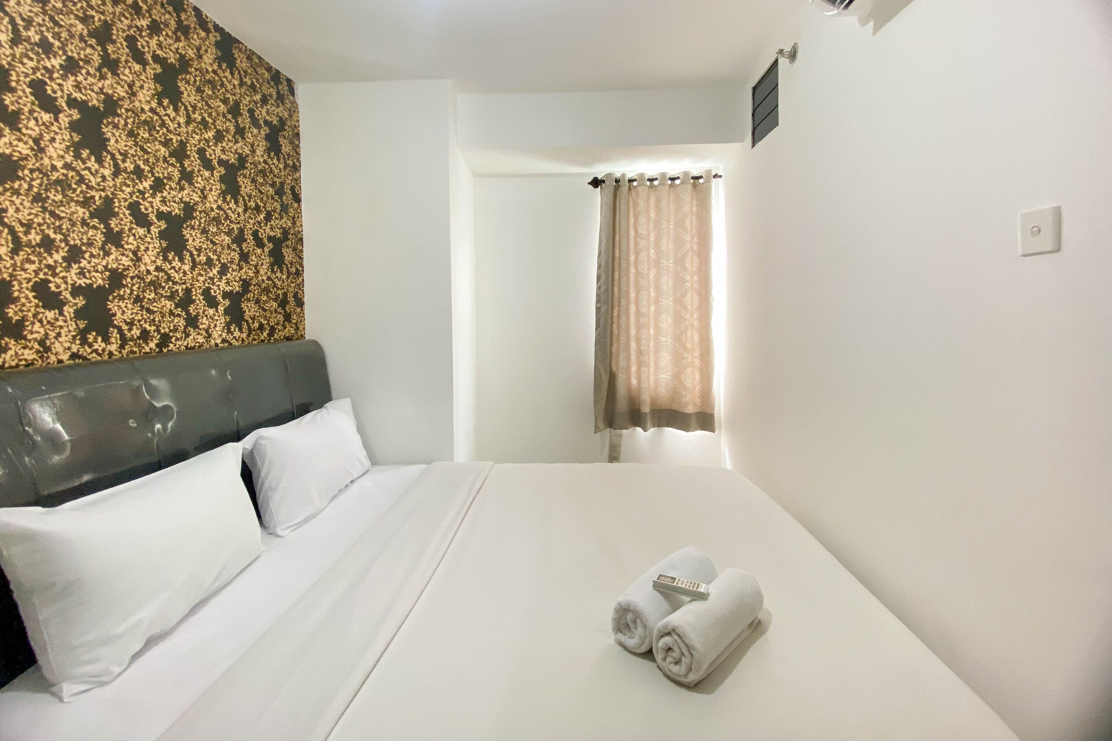 Habitación de hotel con cama, ropa de cama blanca, cabecera, ventana con cortinas y una pared con diseño decorativo.