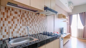 A modern kitchen with a black countertop, stainless steel sink, and a tiled backsplash. - Cozy Stay And Warm Studio Apartment At Margonda Residence 5 (Depok)