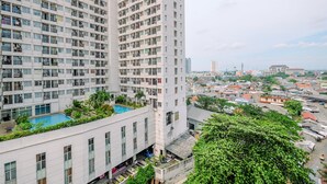 A high-rise building with multiple balconies, a rooftop pool, and a view of a cityscape. - Cozy Stay And Warm Studio Apartment At Margonda Residence 5 (Depok)