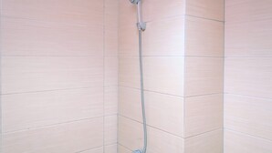 A shower with a handheld showerhead mounted on a wall, with light-colored tiles. - Cozy Stay And Warm Studio Apartment At Margonda Residence 5 (Depok)