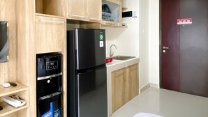 Une cuisine avec des meubles de rangement en bois, un réfrigérateur noir, un four à micro-ondes et un évier.
