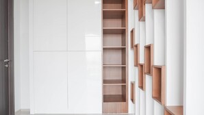 A modern interior with a white wall, a wooden shelving unit, and a door. - Nice And Comfort 1Br At Citralake Suites Apartment (Jakarta)