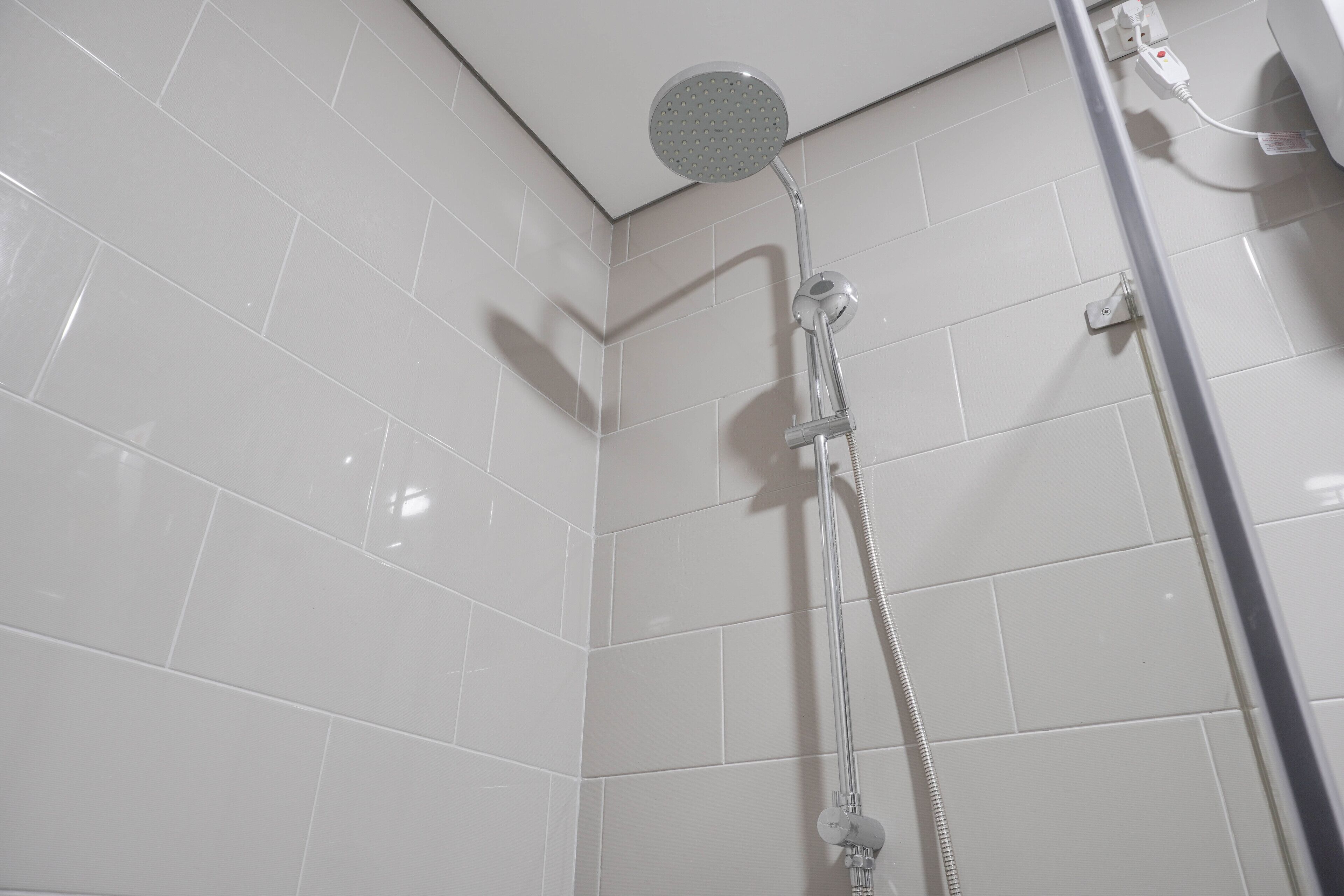 A shower with a handheld showerhead and a wall-mounted faucet.