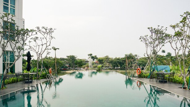 A swimming pool with a clear view of the surrounding area, including trees and a building. - Nice And Comfort 1Br At Citralake Suites Apartment (Jakarta)