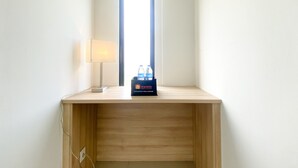 A small wooden desk with a lamp and a box of travel-sized toiletries. - Comfort And Cozy Designed Studio Sayana Bekasi Apartment (Tarumajaya)