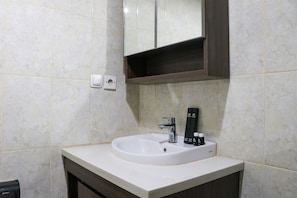 Une salle de bain avec un lavabo blanc, un miroir au-dessus et un meuble en bois foncé en dessous.
