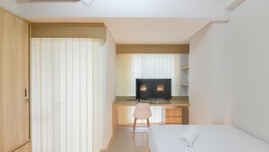 A modern hotel room with a bed, a desk with a television, and a chair. - Luxury Studio At Taman Melati Sinduadi Apartment (Pogung Lor)