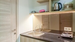 A kitchen with two sinks, a countertop, a kettle, and a coffee maker on a shelf. - Luxury Studio At Taman Melati Sinduadi Apartment (Pogung Lor)