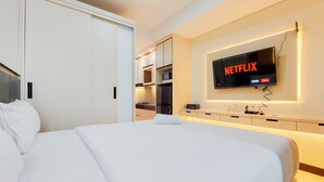 Ein Hotelzimmer mit Bett, Wandfernseher und einer Küchenzeile.