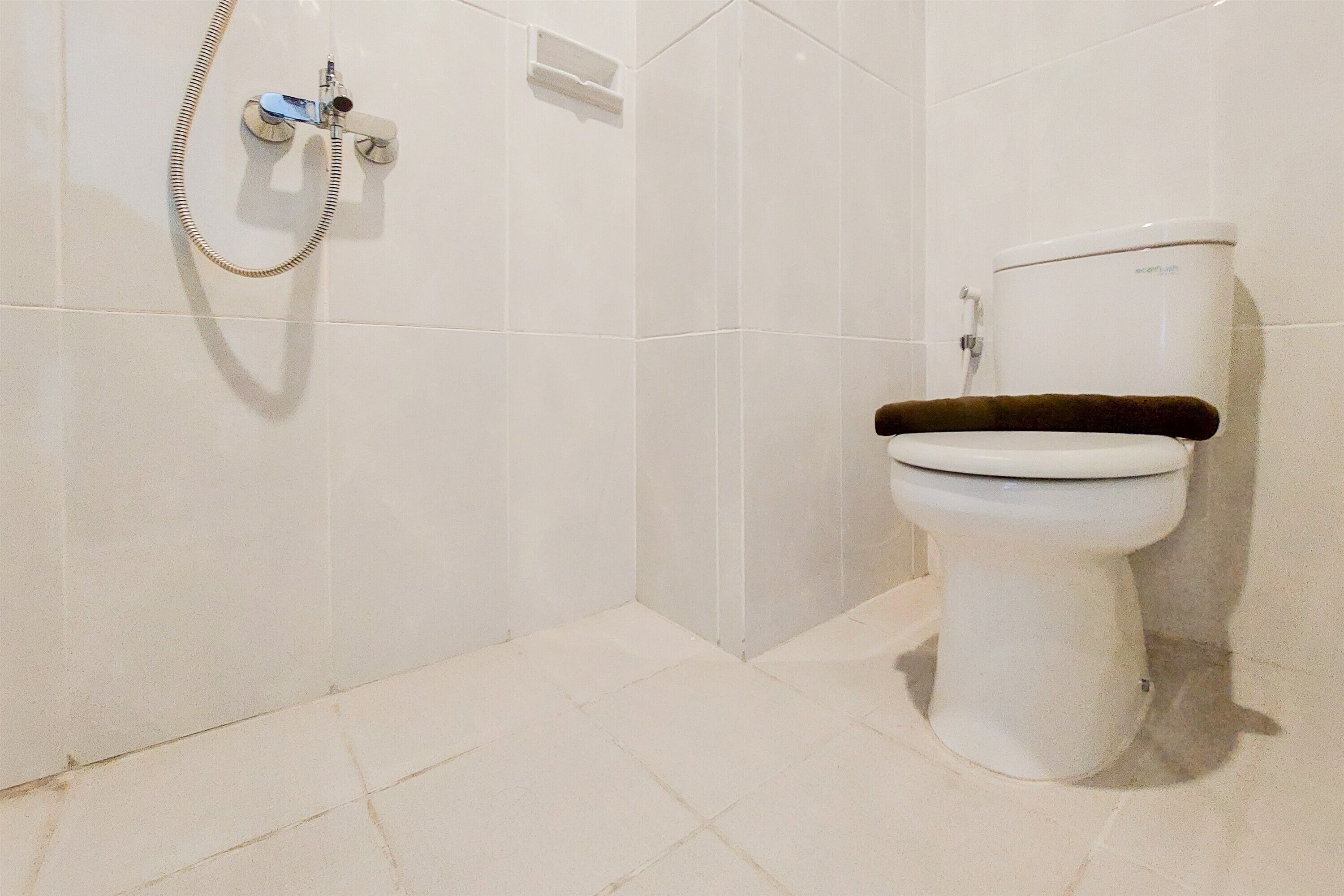 A bathroom with a toilet, a shower, and a wall-mounted toilet paper holder.