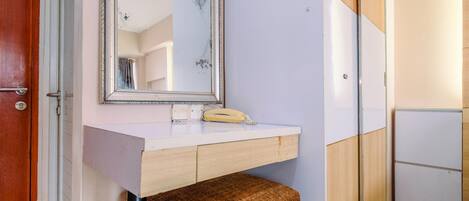 Un baño con un banco de madera, un espejo y una encimera blanca.