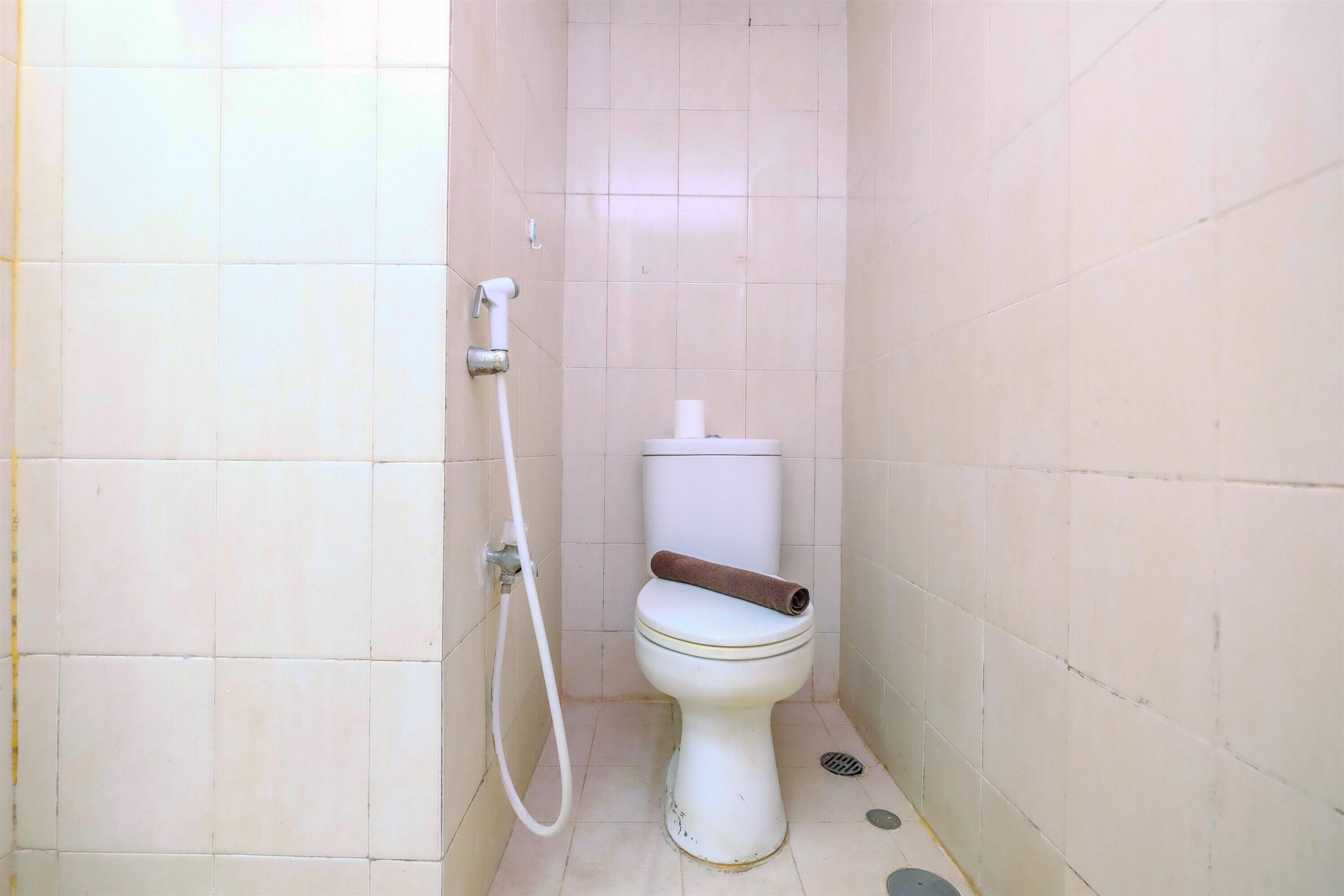 Ein kleines, sauberes Badezimmer mit Toilette, Dusche und Toilettenpapierhalter.