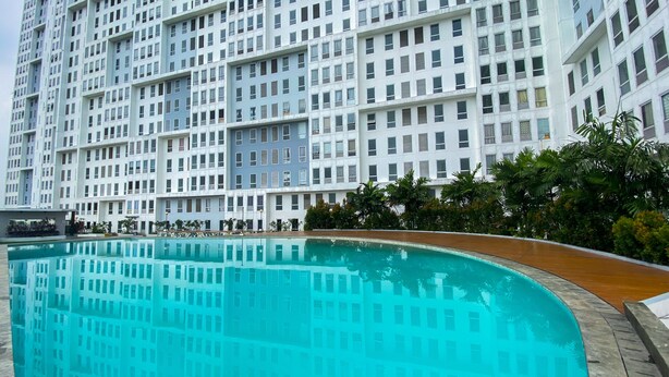 A modern building with a pool in front. - Simply Look 1Br With Extra Room Patraland Urbano Apartment (Bekasi)