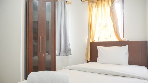 A hotel room with a bed, a wardrobe, and a window with curtains. - Best Homey 2Br Apartment Mediterania Palace Residence (Jakarta)