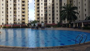 A swimming pool surrounded by a multi-story residential building with balconies. - Best Homey 2Br Apartment Mediterania Palace Residence (Jakarta)