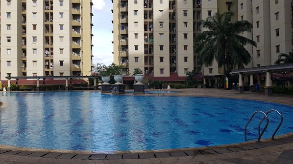 A swimming pool surrounded by a multi-story residential building with balconies. - Best Homey 2Br Apartment Mediterania Palace Residence (Jakarta)
