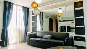 Un salon moderne avec un canapé noir, une table basse en verre et un grand miroir.