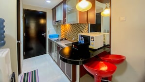 A modern kitchen with a black countertop, red sink, and a tiled backsplash. - Comfort And Well Designed Studio Tamansari Sudirman Apartment (Jakarta)