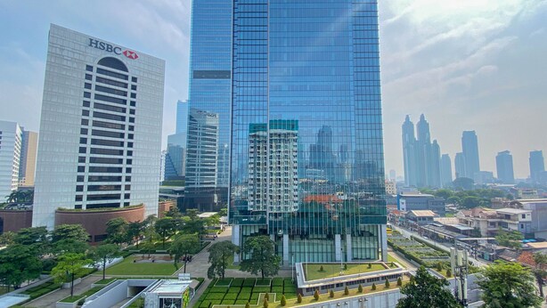 A modern high-rise building with a glass facade, surrounded by other high-rise buildings and greenery. - Comfort And Well Designed Studio Tamansari Sudirman Apartment (Jakarta)