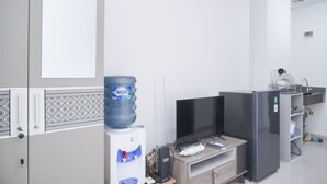 Habitación de hotel moderna con un dispensador de agua grande, un televisor de pantalla plana, un refrigerador y un armario de madera.