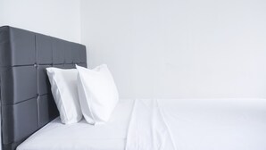 Una cama con cabecera oscura y ropa de cama blanca.