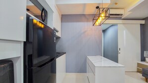 A modern kitchen with a black refrigerator, white cabinets, and a marble countertop. - Comfortable And Minimalist 1Br At The Ayoma Apartment (South Tangerang)