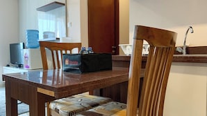 A dining area with a wooden table, chairs, a travelio branded box, a water dispenser, and a television.